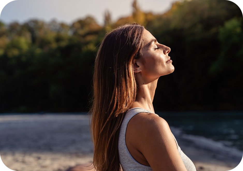Healthy woman on a hike with the sun shining on her face.